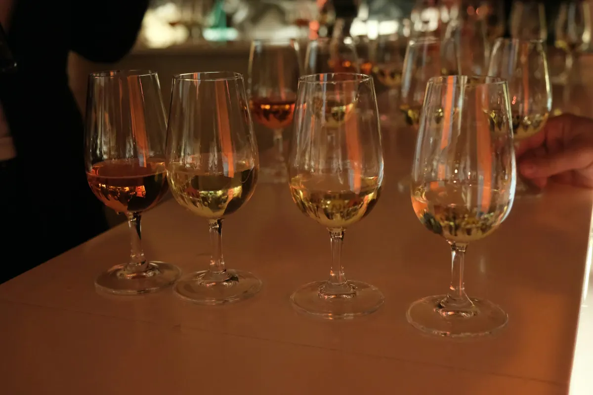 A row of tasting glasses with whisky of different colours on a bar