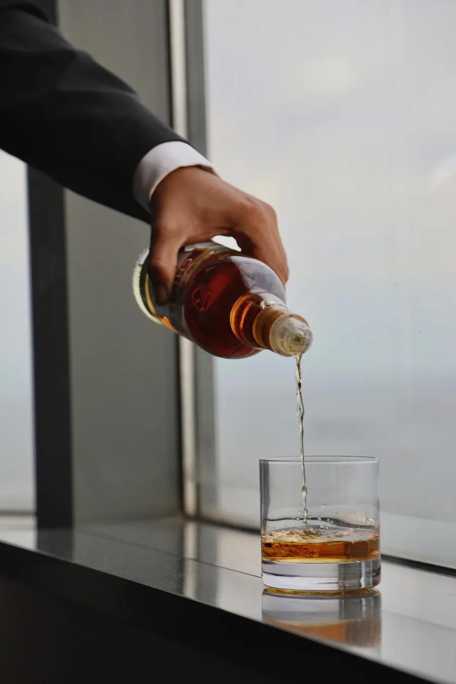 A precise pour beside a floor-to-ceiling city view